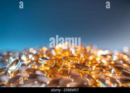 Eine Handvoll goldenes Fischöl Kapseln Omega 3 Vitamine auf Blauer Hintergrund Stockfoto