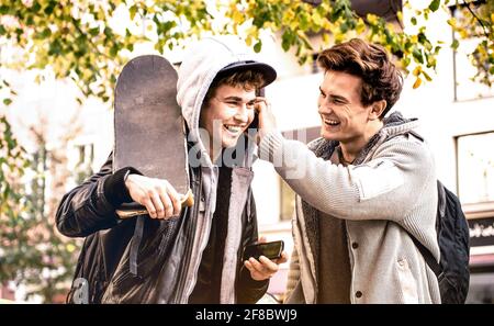 Junge glückliche Brüder, die Spaß mit mobilen Smartphones haben - Die besten Freunde teilen ihre Freizeit mit neuen Trendtechnologien - Freundschaftskonzept Stockfoto
