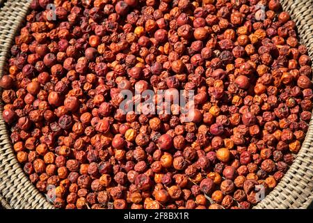 Nahaufgangmakro von kleinen leuchtend roten Früchten in einem traditionellen Korb in Luang Prabang Laos. Stockfoto