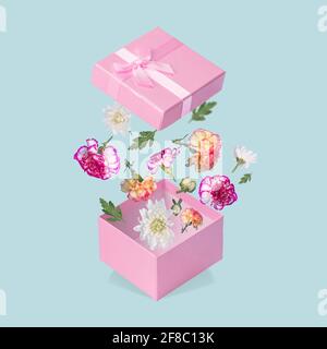 Luxuriöse Geschenkbox mit fliegenden Blüten und Blättern auf pastellblauem Hintergrund. Minimales Frühlings- oder Sommerkonzept. Ein modernes lustiges Konzept von Geschenken Stockfoto