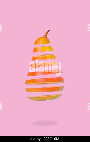 Minimalidee mit schwebenden, reifen Birnen auf pastellrosa Hintergrund. Vitamine, gesunde Ernährung Konzept. Birne in Scheiben, die in der Luft schwebt. Kreative c Stockfoto