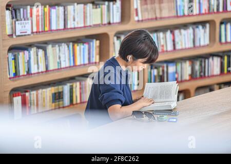 (210413) -- HAIKOU, 13. April 2021 (Xinhua) -- AM 13. April 2021 WIRD EIN Leser in der Wurmloch-Bibliothek in der Haikou-Bucht in Haikou, der Hauptstadt der südchinesischen Provinz Hainan, gesehen. Die Wormhole Library, die als ein Wahrzeichen in der Haikou Bay entworfen wurde, wurde am Dienstag für die Öffentlichkeit geöffnet. (Xinhua/Pu Xiaoxu) Stockfoto