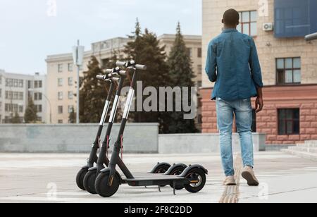 Schwarzer Mann, der in der Nähe von Motorroller zum Verleih läuft Stockfoto