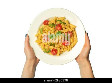 Nudelgerichte auf einem weißen, isolierten Hintergrund mit weiblichen Händen. Italienische Fusilli-Pasta mit Tomaten und Basilikum auf einem weißen Teller. Hochwertige Fotos Stockfoto