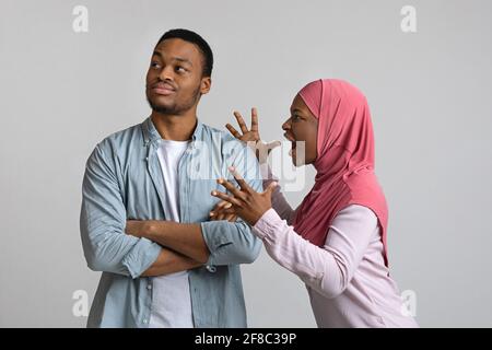 Wütende schwarze Frau im Hijab schrie ihren gleichgültigen Mann an Stockfoto