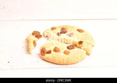 Ein runder duftender, frischer, schmackhafter, süßer, zerbröckelter Plätzchen mit Rosinen, Makro, auf einem Hintergrund aus lackiertem Naturholz. Stockfoto