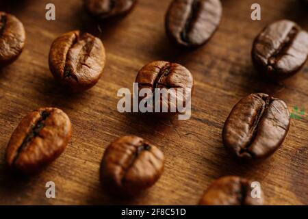 Makroansicht von Kaffeebohnen über dem Kopf, die in einer Reihe angeordnet sind Auf einem Holztisch Stockfoto