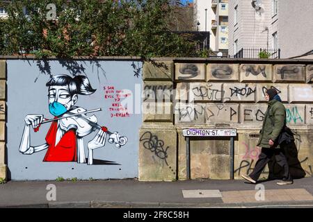 Ein Mann geht an Graffiti vorbei, auf dem ein Geiger mit einer medizinischen Maske abgebildet ist. Covid-19 Pandemie und Lockdown hat Musiker daran gehindert, in der Öffentlichkeit aufzutreten. Stockfoto