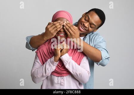 Liebevoller schwarzer Kerl, der seine emotionale Freundin mit den Augen bedeckt Stockfoto