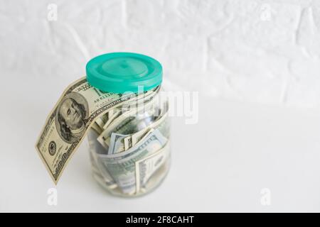 Faltet Geld in einem Glas auf einem weißen Holzhintergrund. Der Ort des Hintergrundbildes für Text. Stockfoto