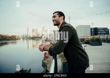 Gemischter Rassenmännchen, der sich gegen das Geländer der Brücke lehnt, in der er steht Hafen Stockfoto