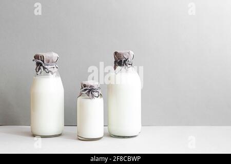 Minimale Standzeit von Milchflaschen auf hellem Hintergrund mit Platz für Kopien. Milchproduktion, Bio-Produkt. Das Konzept der gesunden Ernährung und Sustain Stockfoto