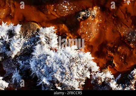 Die kreative Eleganz der Natur: Eisskulpturen, Eisblumen und Reifrost, kombiniert mit dem klaren Wasser und den eisenroten Felsen des Yukon River. Stockfoto