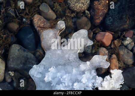 Die kreative Eleganz der Natur: Eisskulpturen, Eisblumen und Reifrost, kombiniert mit dem klaren Wasser und den farbigen Felsen des Yukon River. Stockfoto