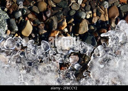 Die kreative Eleganz der Natur: Eisskulpturen, Eisblumen und Reifrost, kombiniert mit dem klaren Wasser und den farbigen Felsen des Yukon River. Stockfoto