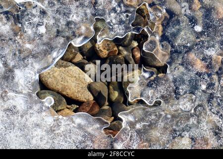 Die kreative Eleganz der Natur: Eisskulpturen, Eisblumen und Reifrost, kombiniert mit dem klaren Wasser und den farbigen Felsen des Yukon River. Stockfoto