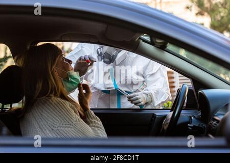Medizinisches Personal Durchführen Drive-Thru COVID-19 Test, unter nasalen Tupfer Probe von weiblichen Patienten durch Auto-Fenster, PCR-Diagnose für Coronavirus, d Stockfoto