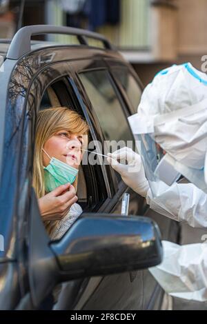 Medizinisches Personal Durchführen Drive-Thru COVID-19 Test, unter nasalen Tupfer Probe von weiblichen Patienten durch Auto-Fenster, PCR-Diagnose für Coronavirus, d Stockfoto