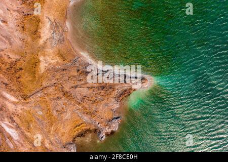 Luftaufnahme über felsige Küste mit türkisfarbenem, winkenden Wasser. Stockfoto