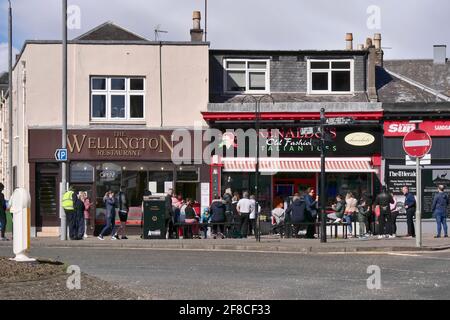 Während der Covid-Sperre im Frühjahr 2021 warten die Leute vor dem Fisch- und Chipshop von Wellington und dem italienischen Eisdielen-Laden Renaldos. Ayr, Schottland, Großbritannien Stockfoto