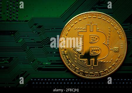 Goldene Münzen mit Bitcoin-Symbol auf grünem Mainboard-Hintergrund. Kryptowährung, Geldmünze digital. Blockchain-Technologie, Bitcoin-Mining. Stockfoto