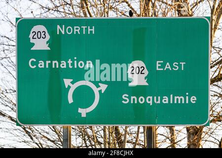 Ein grün-weißes Verkehrsschild weist auf einen Kreisverkehr hin, der die Autobahnen 202 und 203 verbindet. Diese Straßeninseln sind im Snoqualmie Valley häufig geworden Stockfoto