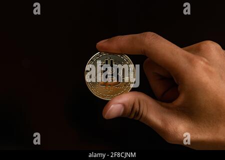 Nahaufnahme einer goldenen Münze mit dem Bitcoin-Symbol in der Hand. Junge Hand hält Kryptowährung Münze, Geld Münzen digital, BTC Stockfoto