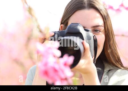 Vorderansicht Porträt eines Fotografen, der Blumen mit Makro fotografiert Objektiv und dslr-Kamera im Feld Stockfoto