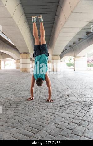 Man macht einen Handstand unter einer Brücke in Valencias Stadt der Künste und Wissenschaften, Spanien. Stockfoto