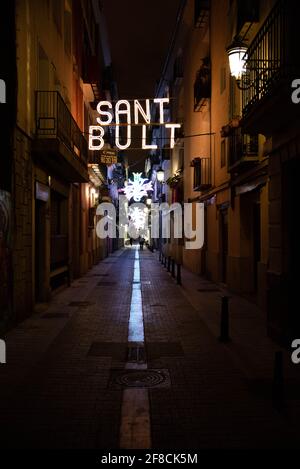 Eine dunkle Gasse in der Altstadt von Valencia, beleuchtet von einem Straßenschild mit der Aufschrift Sant Bult in Valencia, Spanien. Stockfoto