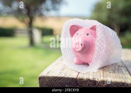 Sparschwein in Luftpolsterfolie verpackt, schützt Ihre Ersparnisse und Ihr Geld Stockfoto