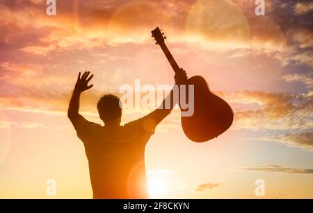 Silhouette des Gitarristen Musiker hält Gitarre gegen Sonnenuntergang Konzept für Religion oder Musikfestival Stockfoto