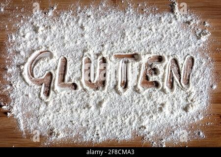 Gluten Wort in Mehl auf Backbrett geschrieben Konzept für Allergenpflege und Intoleranz Stockfoto