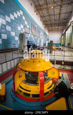 Maschinenraum des Wasserkraftwerks Shardara. Gelbe Generatormaschine und Arbeiter. Kasachstan. Stockfoto