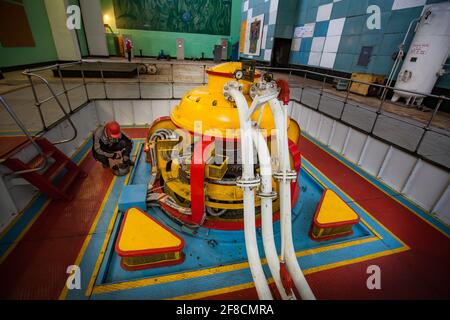 Maschinenraum des Wasserkraftwerks Shardara. Gelbe Generatormaschine und Wartungsarbeiter. Kasachstan. Stockfoto