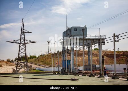 Teil des Wasserkraftwerks und Staudamm am Fluss Shardara. Portalkran rechts, Elektromast links. Blauer Himmel. Stockfoto