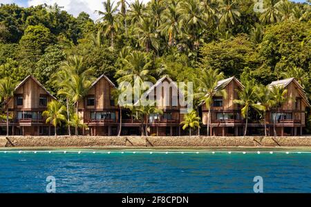 Wunderschönes Resort auf den Philippinen. Topische Hütten und Häuser am Strand mit blauem Meer und herrlichem sonnigem Wetter. Große, hohe Kokospalmen. Stockfoto