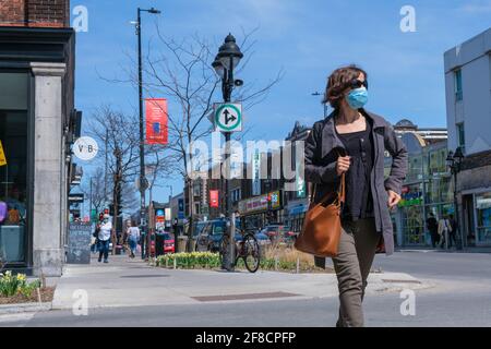 Montreal, CA - 11. April 2021: Fußgänger mit Gesichtsmaske zum Schutz vor COVID-19, der die Straße entlang geht Stockfoto