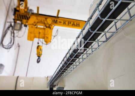 Shchuchinsk Stadt, Kasachstan - 16. April 2012: Kabelhalter und gelber Kran. Kran ist verschwommen. Abstraktes Industriefoto Stockfoto