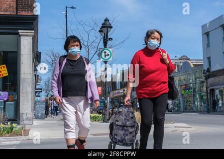 Montreal, CA - 11. April 2021: Fußgänger mit Gesichtsmasken zum Schutz vor COVID-19 gehen die Straße hinunter Stockfoto