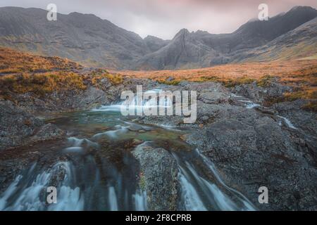 Stimmungsvolle Berg- und Wasserfalllandschaft der Feen Pools und Schwarze Cuillins bei Sonnenuntergang oder Sonnenaufgang bei Glenspröde auf dem Isle of Skye im Schotten Stockfoto