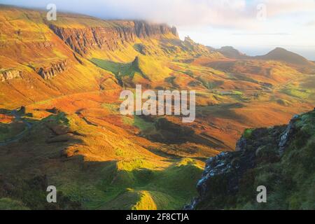 Lebendiges goldenes Licht bei Sonnenuntergang oder Sonnenaufgang über der farbenfrohen Landschaft des rauen, weltfremden Geländes des Quiraing auf der Isle of Skye, Scotl Stockfoto