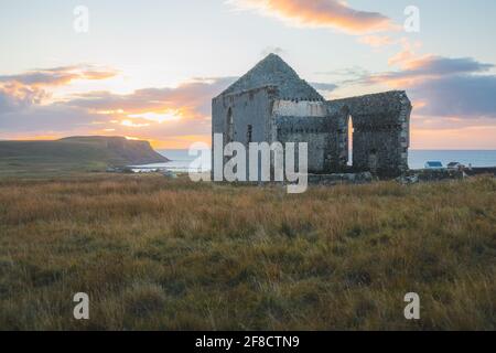 Alte, alte Steinruinen der abgelegenen und isolierten Kilmuir Church in der schottischen ländlichen Küstenlandschaft bei Sonnenuntergang oder Sonnenaufgang auf der Isle of Skye, Stockfoto