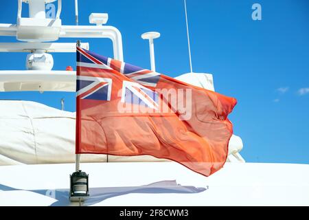 Die Flagge des Vereinigten Königreichs winkt auf dem Heck der Yacht. Red Duster ist ein britischer ziviler Fähnrich. Das britische Luxusboot liegt in einem Yachthafen. Blauer Himmel, Nahaufnahme Stockfoto