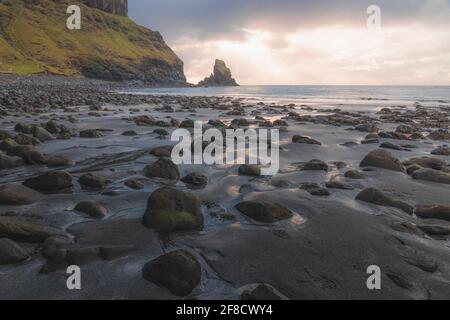 Goldenes Sonnen- oder Sonnenaufgangslicht auf Meereslandschaft und Meer bei Ebbe entlang der felsigen Küste am Talisker Bay Beach auf der Isle of Skye, Schottland Stockfoto