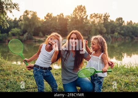 Muttertag. Die Familie hat Spaß, nachdem sie Badminton am Summer River gespielt hat. Mutter lachte und grimazing mit Töchtern im Freien. Stockfoto