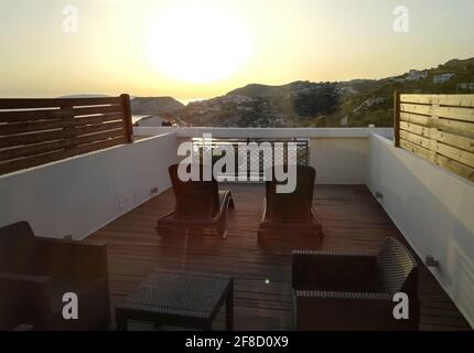 Santorini, Griechenland: Tische und Stühle auf großer Terrasse Dachbalkon mit einem schönen romantischen Blick auf die Hügel, Meer und Sonnenuntergang Sonnenaufgang von berühmten gre Stockfoto