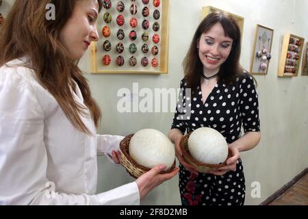 KHARKIV, UKRAINE - 13. APRIL 2021 - die Besucher halten große Ostereier während der Osterwunderausstellung im Regional Organizational and Methodical C Stockfoto