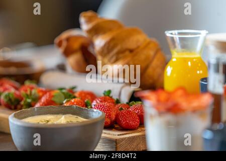 Das Frühstück wird mit Kaffee, Orangensaft, Croissants, Müsli und Obst serviert Stockfoto