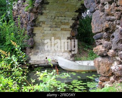 Steinbogen mit einem alten Boot im Wörlitzer Park Stockfoto